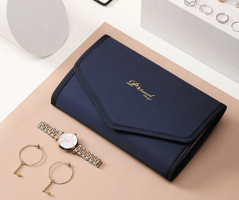 Elegant and portable navy blue travel jewelry bag with multiple compartments for organizing rings, necklaces, and earrings.