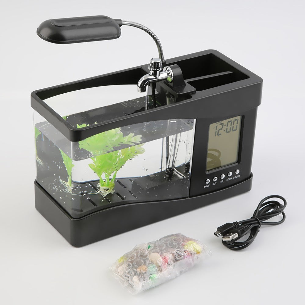 "Mini Aquarium Office Desk Organizer β A multifunctional desk accessory featuring an aquarium, LED table lamp, calendar, alarm, and pen holder, complete with small pebbles and a plant, creating a calming workspace atmosphere."