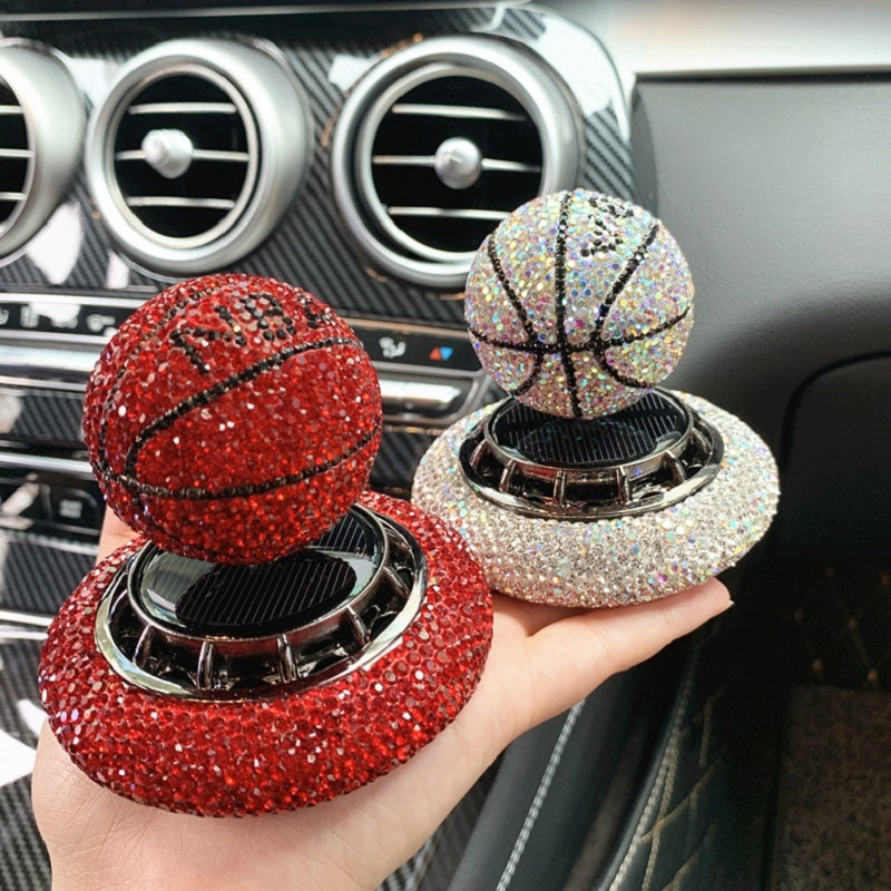 Solar-powered basketball ornament with diamond-encrusted design, rotating with sunlight. Includes solid aromatherapy for a pleasant fragrance. Available in red, white, and blue with a non-slip base.