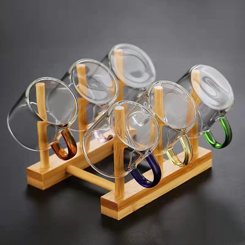 A beautifully arranged Thick Glass Transparent Tea Set, featuring a minimalist design with high borosilicate glass. The set includes six elegant tea cups and a matching cup holder, perfect for serving tea. Available in various sizes and styles, including transparent and colorful options with long spout pots.