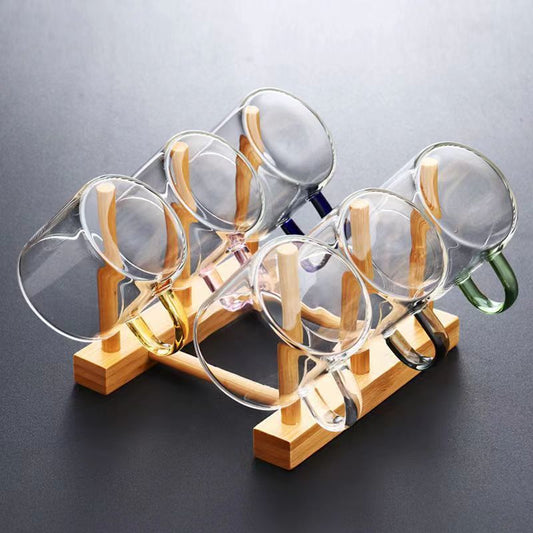 A beautifully arranged Thick Glass Transparent Tea Set, featuring a minimalist design with high borosilicate glass. The set includes six elegant tea cups and a matching cup holder, perfect for serving tea. Available in various sizes and styles, including transparent and colorful options with long spout pots.