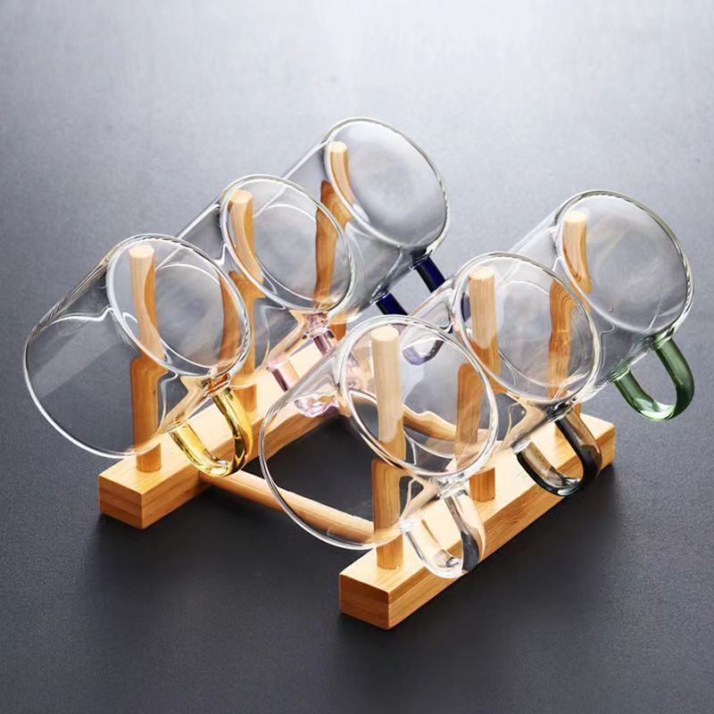 A beautifully arranged Thick Glass Transparent Tea Set, featuring a minimalist design with high borosilicate glass. The set includes six elegant tea cups and a matching cup holder, perfect for serving tea. Available in various sizes and styles, including transparent and colorful options with long spout pots.
