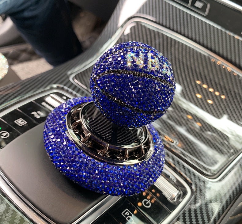 Solar-powered basketball ornament with diamond-encrusted design, rotating with sunlight. Includes solid aromatherapy for a pleasant fragrance. Available in red, white, and blue with a non-slip base.