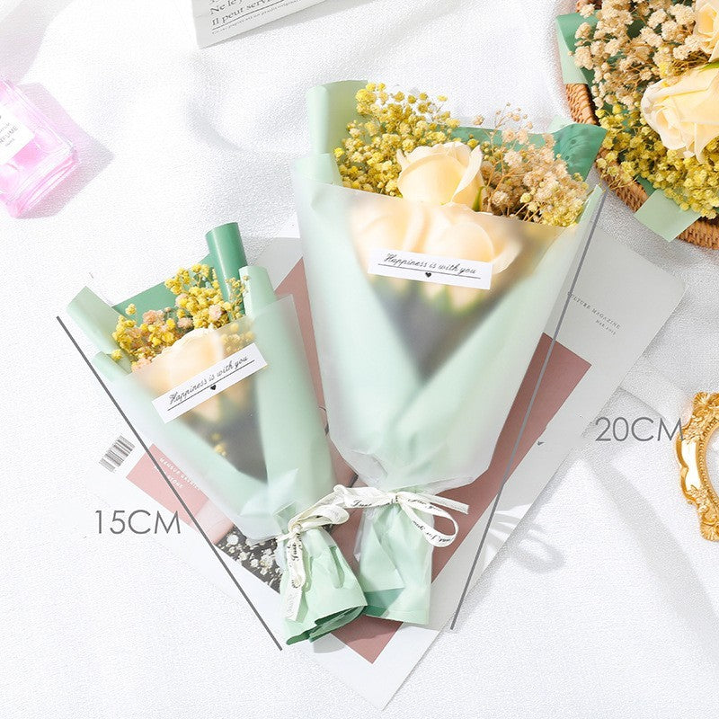 **"Elegant soap flower bouquet featuring delicate roses, forget-me-nots, and carnations, beautifully wrapped in premium paper with a gold ribbon. A timeless gift for weddings, birthdays, and special occasions."**