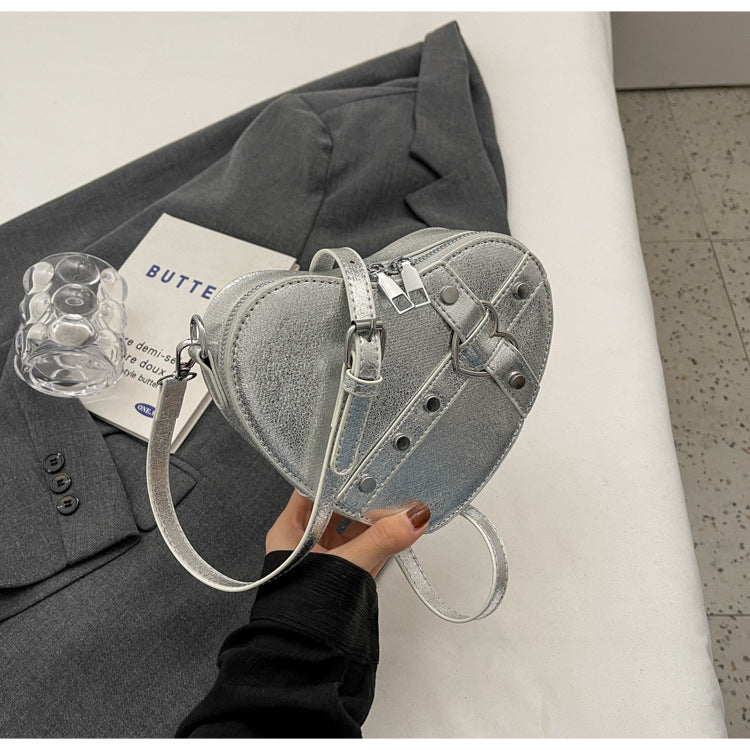 Cute heart-shaped shoulder messenger bag made of soft PU material, featuring a zipper change bag inside. Available in black, cream white, silver, and wine red, with a single shoulder strap and an urban simplicity style for everyday use.