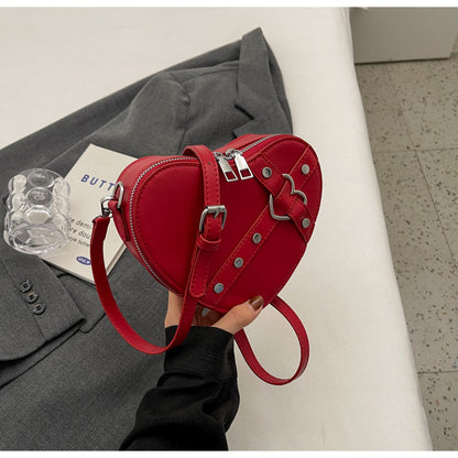 Cute heart-shaped shoulder messenger bag made of soft PU material, featuring a zipper change bag inside. Available in black, cream white, silver, and wine red, with a single shoulder strap and an urban simplicity style for everyday use.