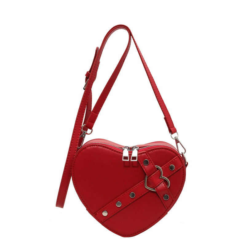 Cute heart-shaped shoulder messenger bag made of soft PU material, featuring a zipper change bag inside. Available in black, cream white, silver, and wine red, with a single shoulder strap and an urban simplicity style for everyday use.