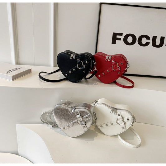 Cute heart-shaped shoulder messenger bag made of soft PU material, featuring a zipper change bag inside. Available in black, cream white, silver, and wine red, with a single shoulder strap and an urban simplicity style for everyday use.