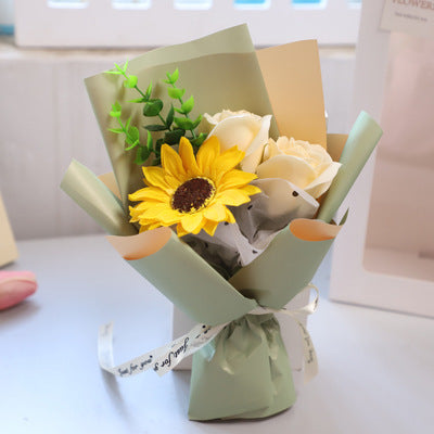 **"Elegant soap flower bouquet featuring delicate roses, forget-me-nots, and carnations, beautifully wrapped in premium paper with a gold ribbon. A timeless gift for weddings, birthdays, and special occasions."**