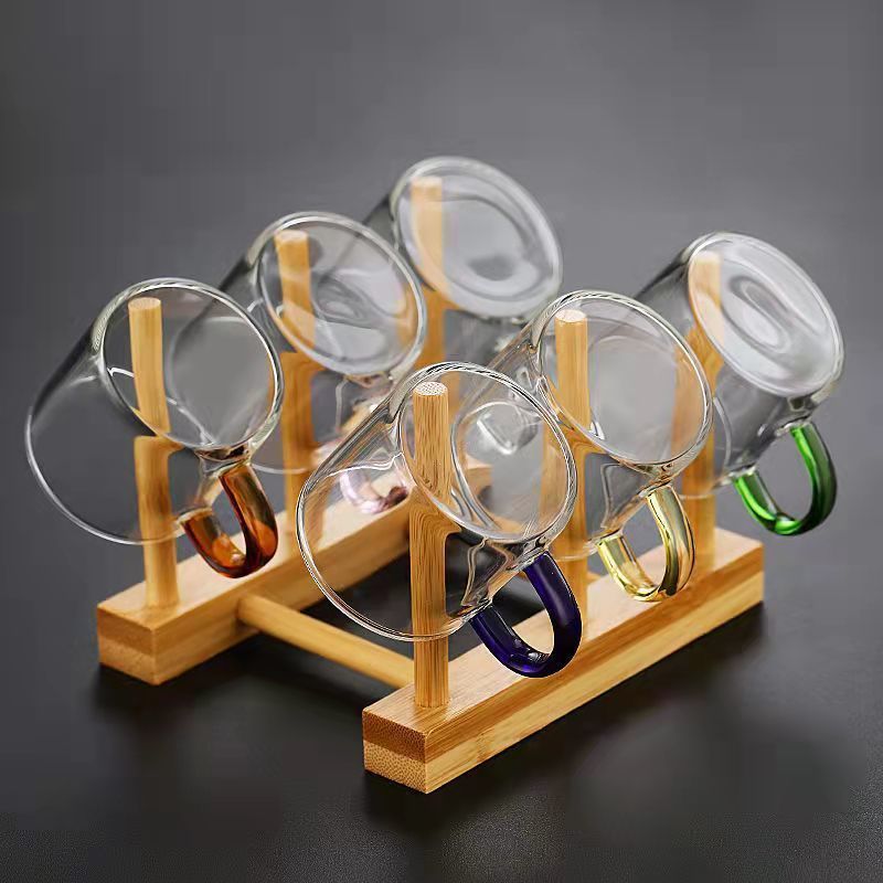 A beautifully arranged Thick Glass Transparent Tea Set, featuring a minimalist design with high borosilicate glass. The set includes six elegant tea cups and a matching cup holder, perfect for serving tea. Available in various sizes and styles, including transparent and colorful options with long spout pots.