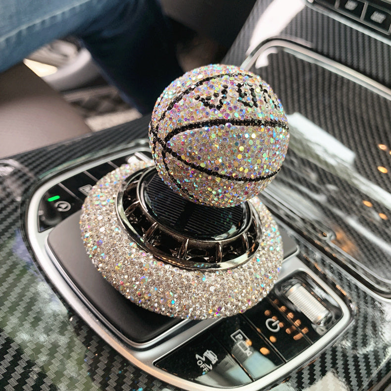 Solar-powered basketball ornament with diamond-encrusted design, rotating with sunlight. Includes solid aromatherapy for a pleasant fragrance. Available in red, white, and blue with a non-slip base.