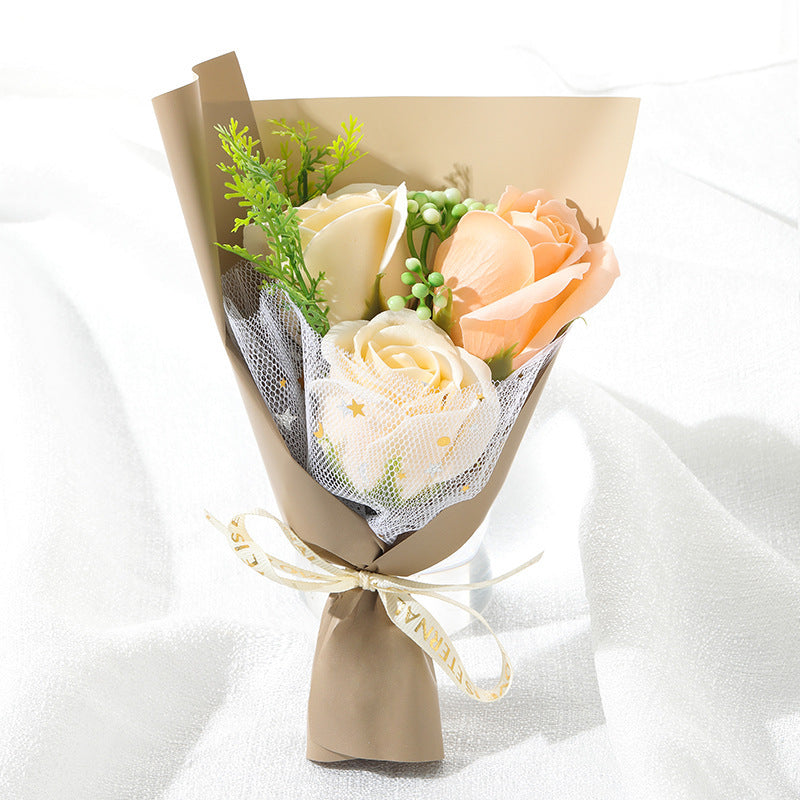 **"Elegant soap flower bouquet featuring delicate roses, forget-me-nots, and carnations, beautifully wrapped in premium paper with a gold ribbon. A timeless gift for weddings, birthdays, and special occasions."**